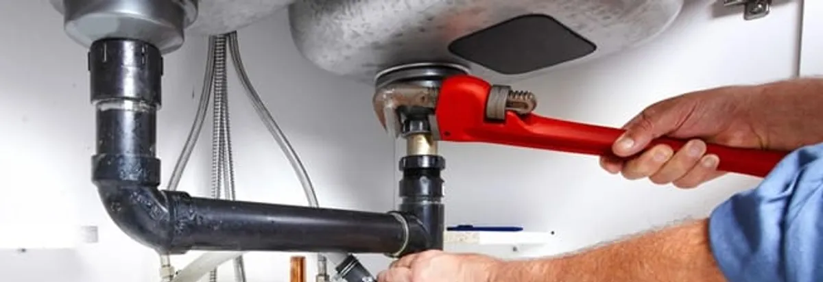 Garbage disposal repair technician tightening the sink drain and disposal connection in Denver, CO