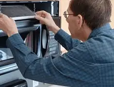 Appliance repair technician replacing a microwave vent filter in Denver, CO