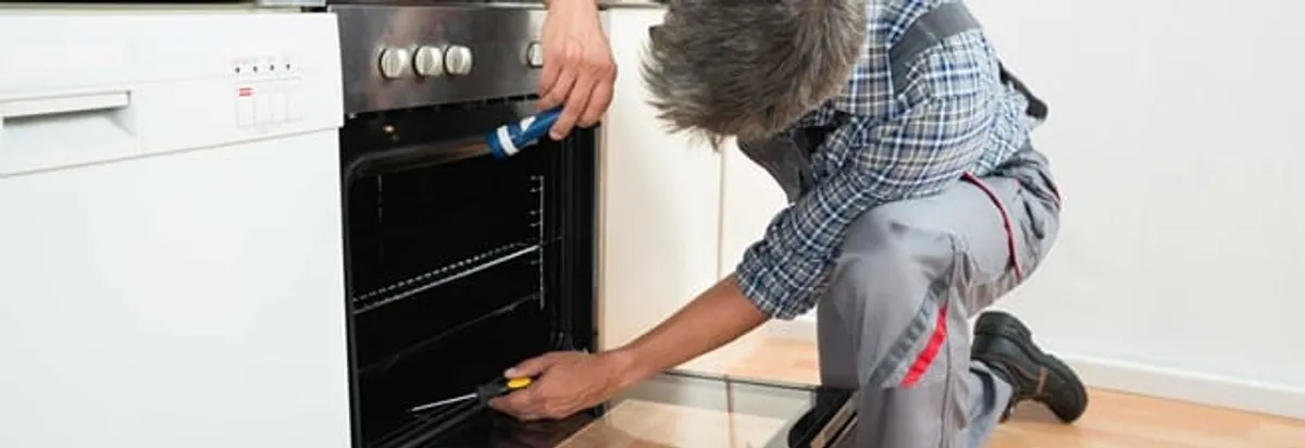 Oven repair technician inspecting and servicing an electric oven in Denver, CO