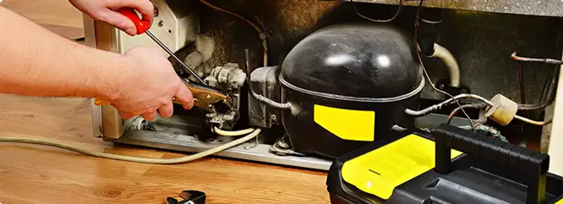 Refrigerator repair technician fixing the compressor and wiring in Denver, CO